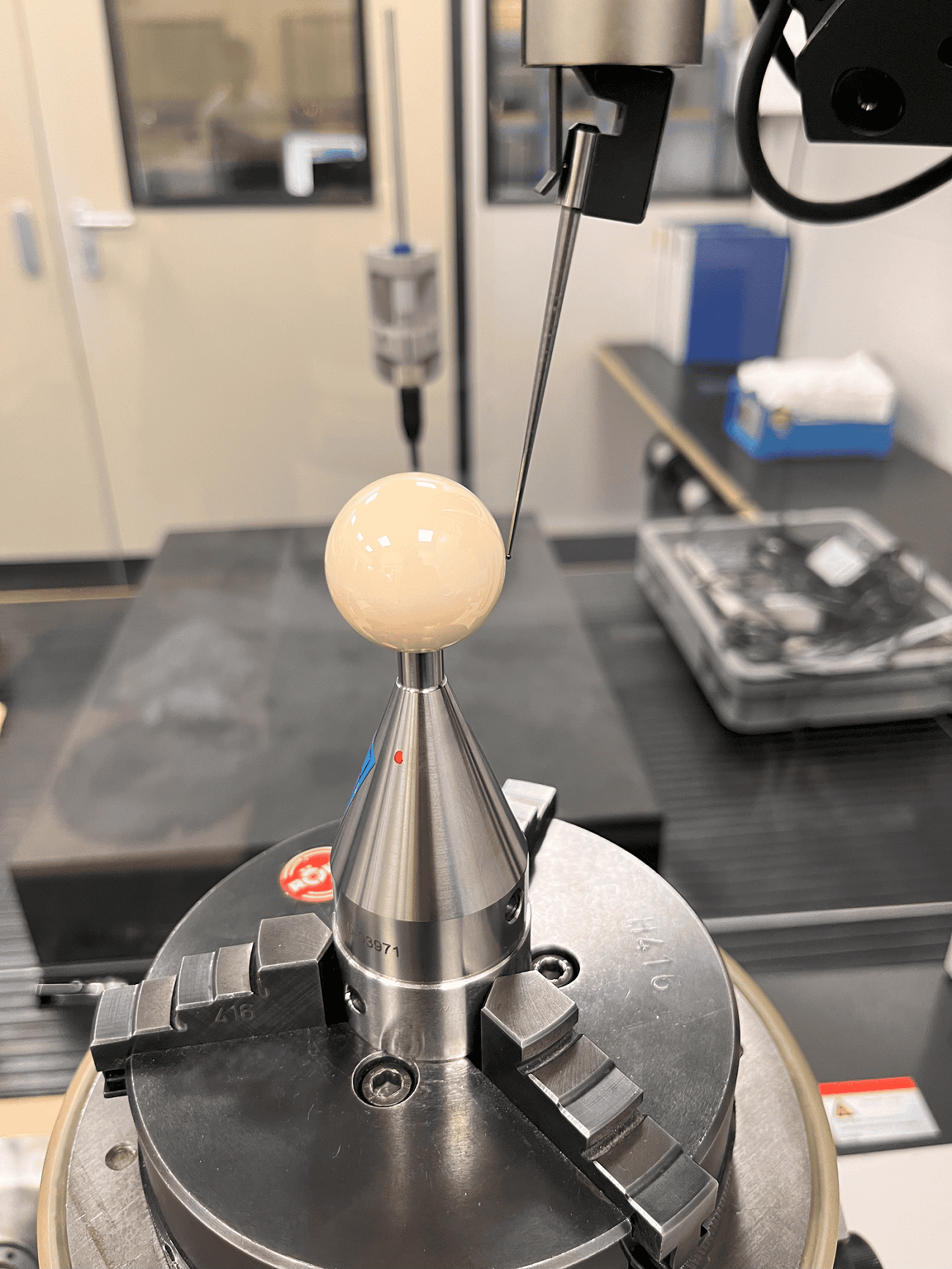 The stylus of a RONDCOM is measuring the roundness of a ball as a reference standard.